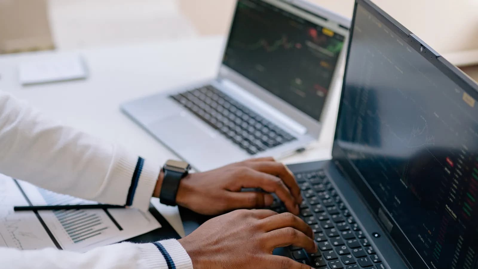 Person analysing data across two laptops